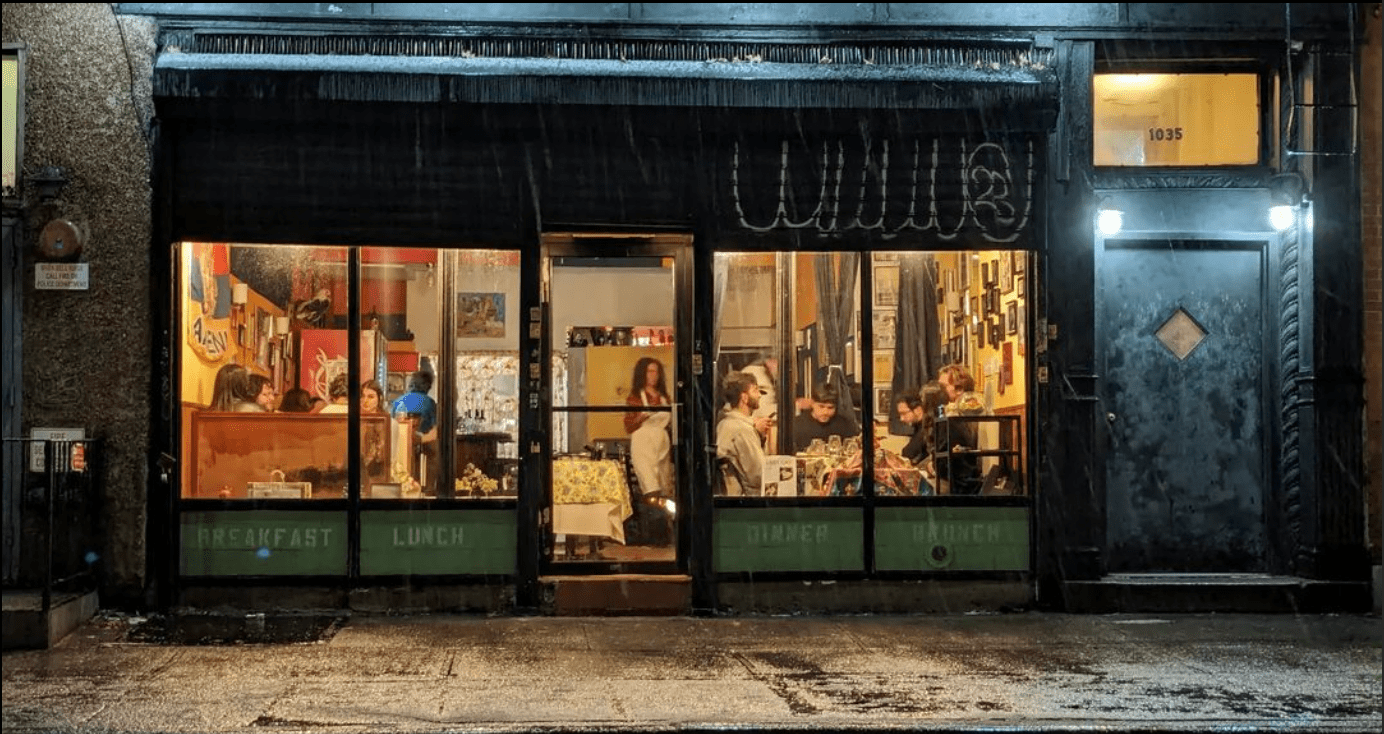 Cafe Little Armenia at night — warm light and guests visible through the windows